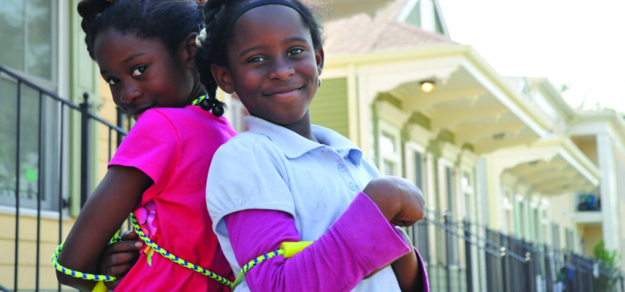 two smiling black girls standing back-to-back